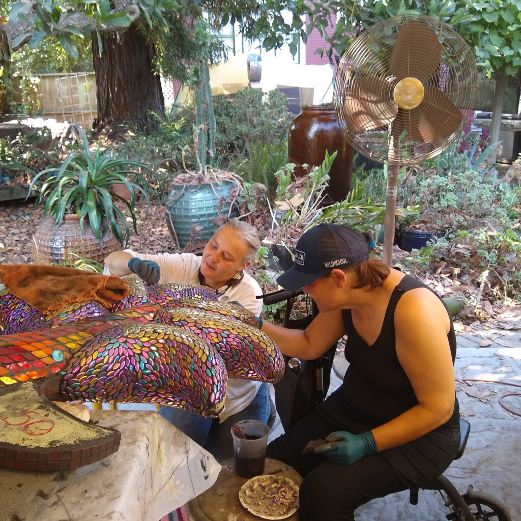 Best friends helping place tesserae onto the dragon.