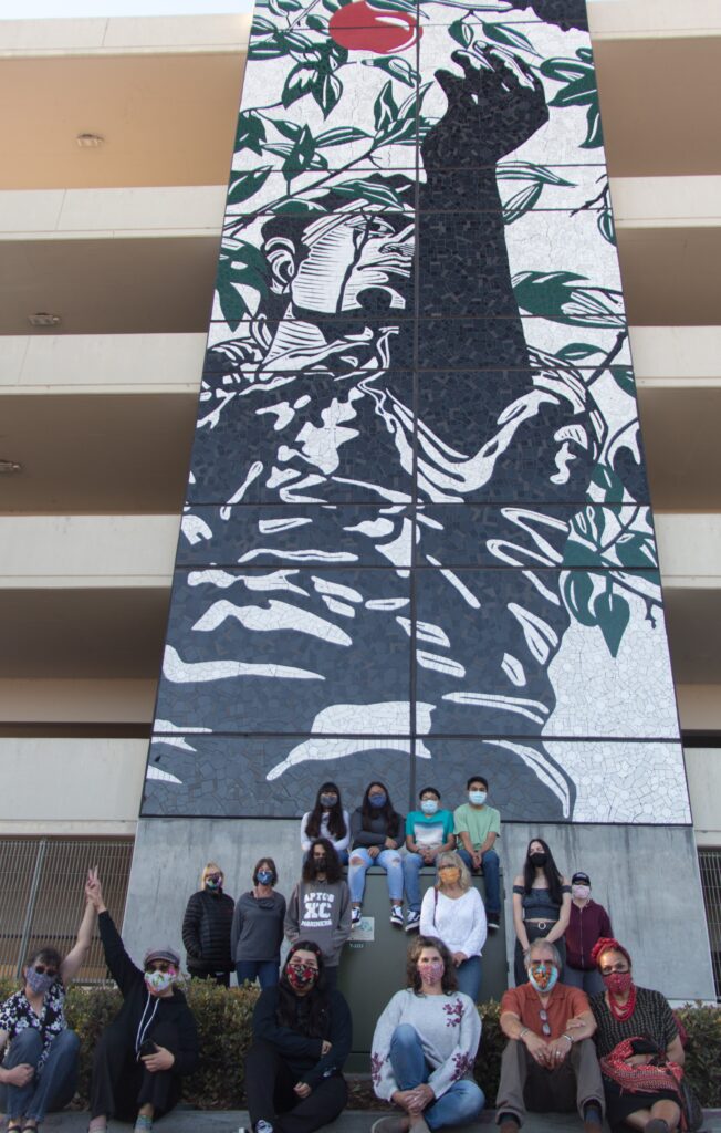 The team of volunteers that created En el Cielo (The Apple Picker), beneath the completed and installed mural.