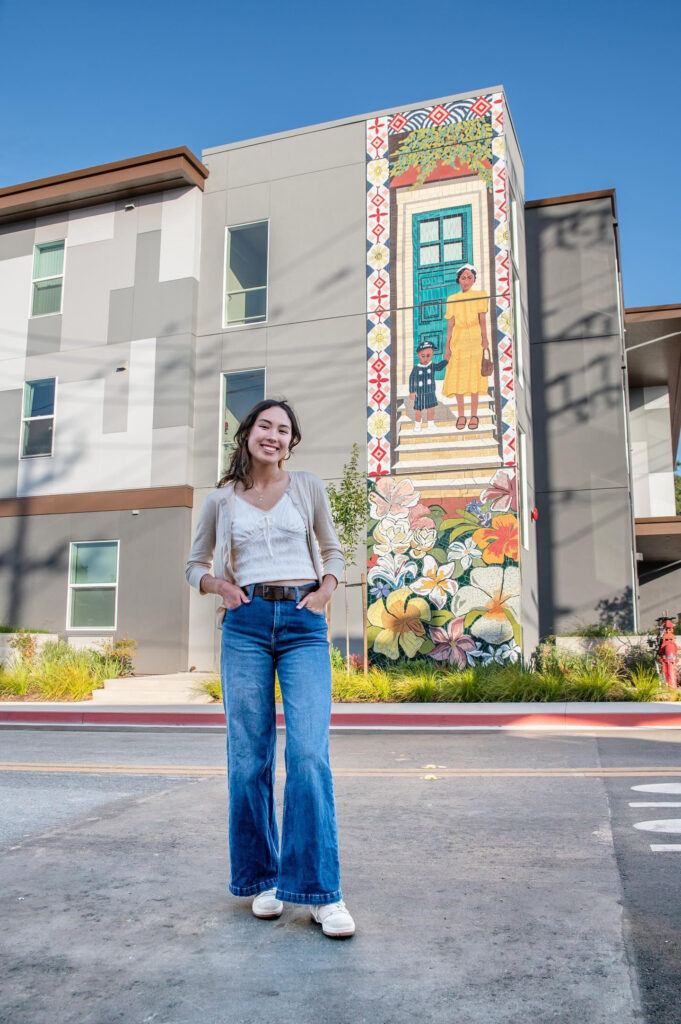 Caitlin Bayaca in front of the completed mural she designed